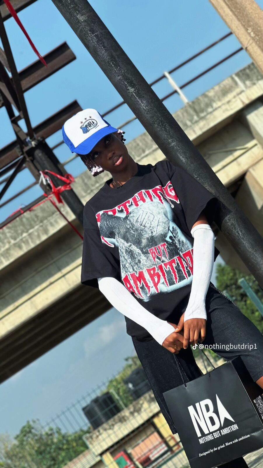 Model wearing the black NBA graphic tee, holding an NBA shopping bag